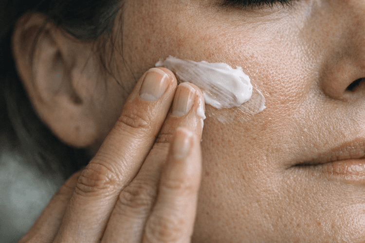 A person applying a ceramide cream on their face.